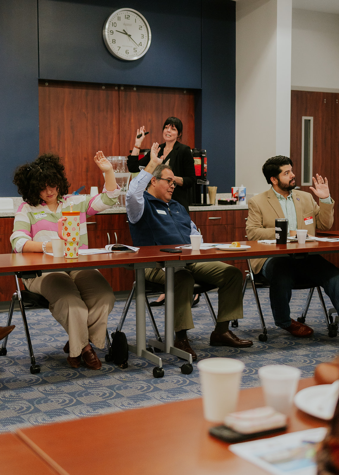 Hands raised in response during a community meeting