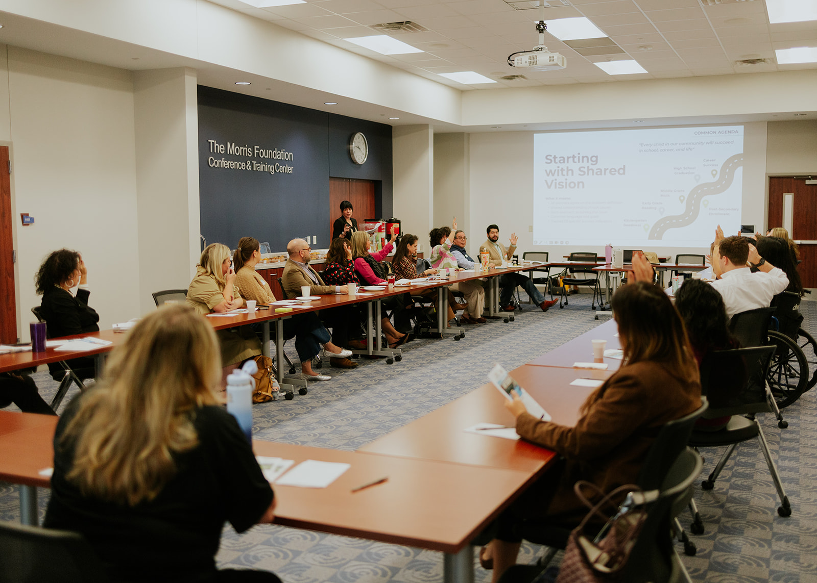 Wide view of nonprofit professionals around a U-shaped table at a Monthly Meeting